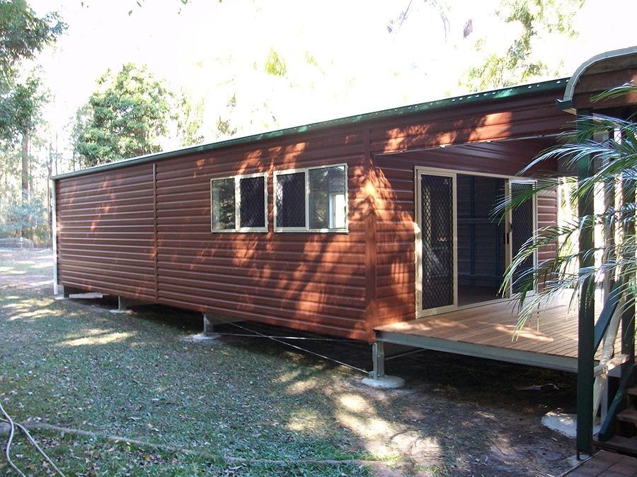 A Wooden House With a Porch and a Lot of Windows — Just Sheds In Kunda Park, QLD