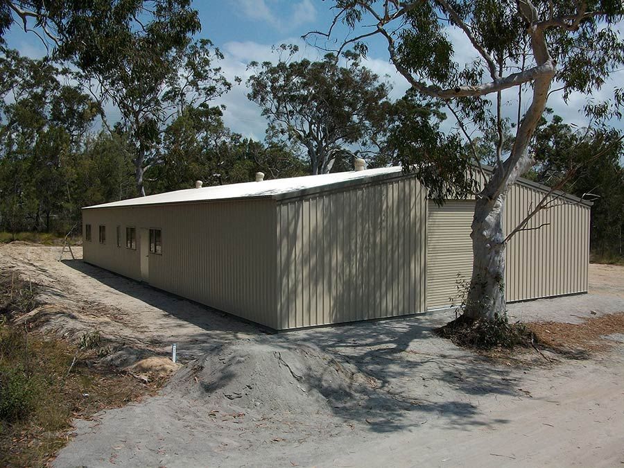 A Large Building With a White Roof and a Tree in Front of It — Just Sheds In Kunda Park, QLD