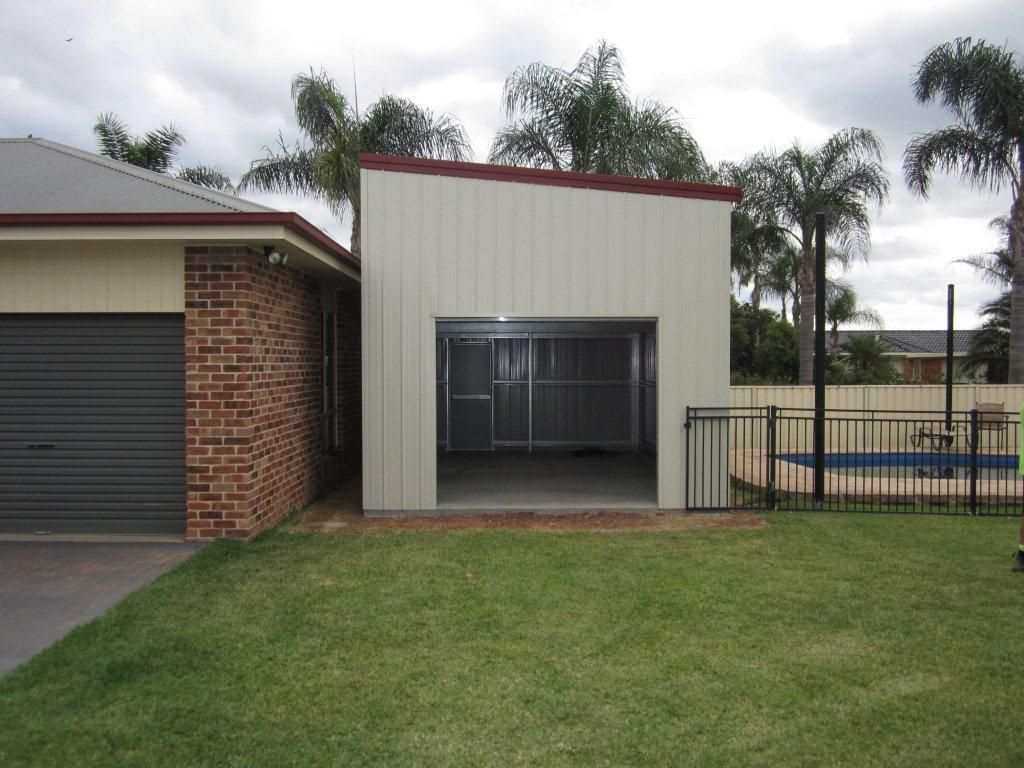 A Brick House With a Garage Next to It — Just Sheds In Kunda Park, QLD
