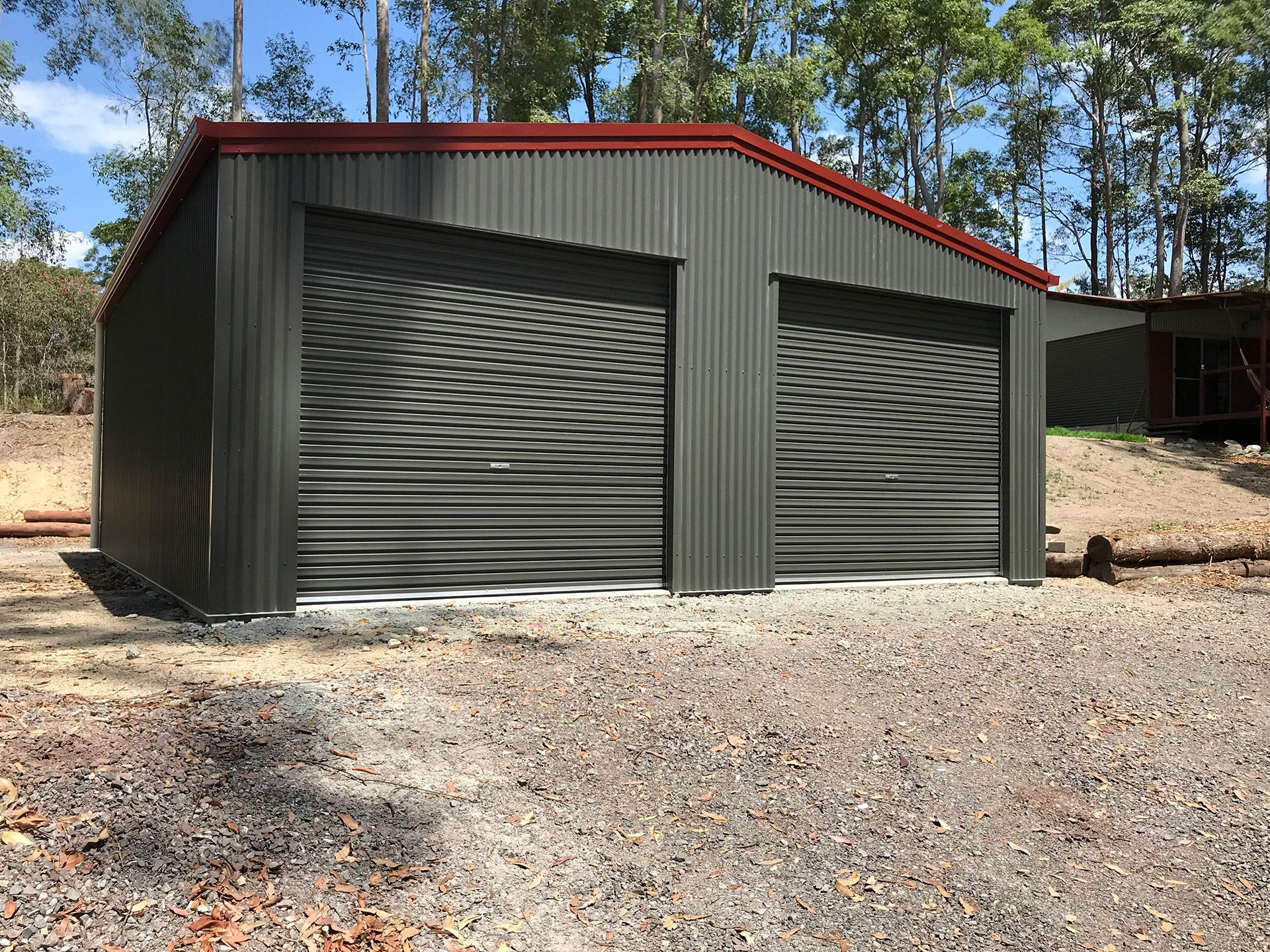 A Garage With Two Garage Doors is Sitting on Top of a Gravel Lot — Just Sheds In Kunda Park, QLD
