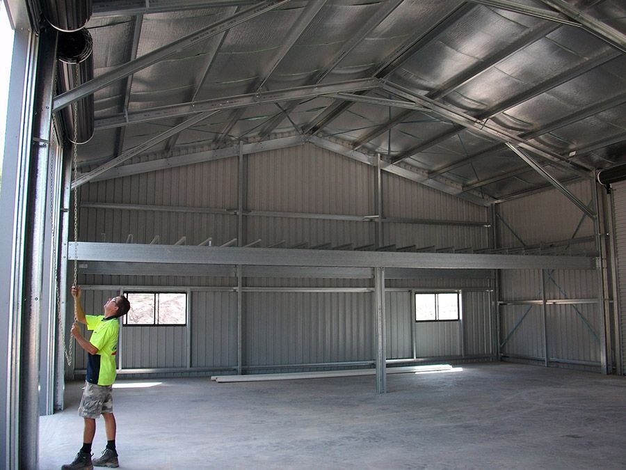 A Man in a Yellow Shirt is Standing in an Empty Building — Just Sheds In Kunda Park, QLD