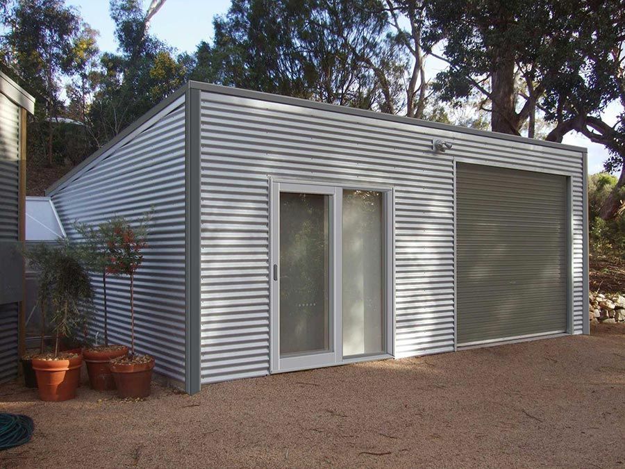 A Garage With a Sliding Glass Door and Trees in the Background — Just Sheds In Kunda Park, QLD