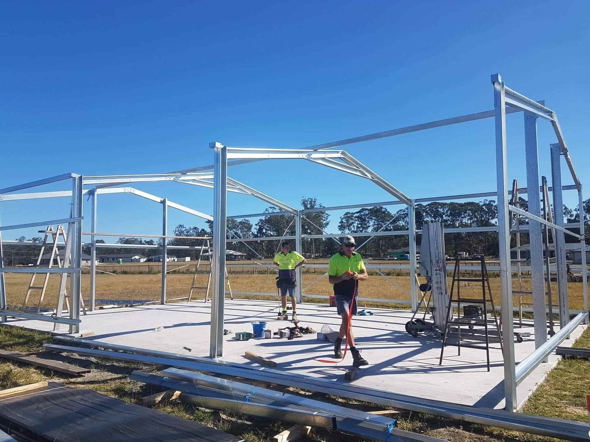 Two Men Are Working On A Metal Structure In A Field — Just Sheds In Brendale, QLD