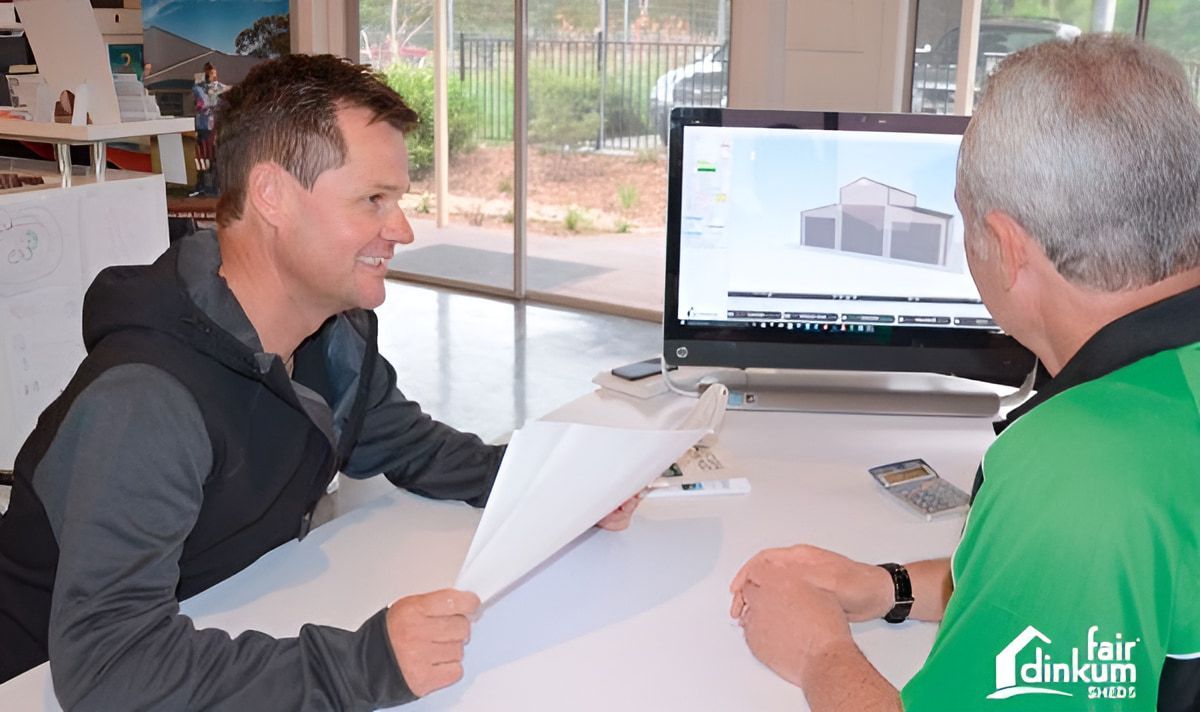 Two men are sitting at a table looking at a computer screen. — Just Sheds In Kunda Park, QLD