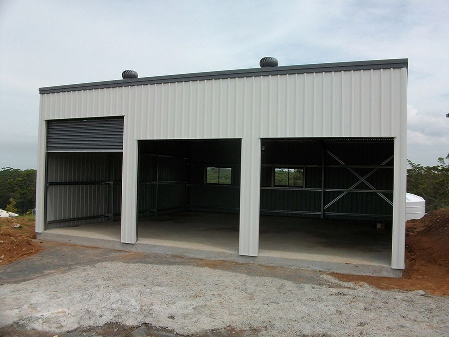 A White Building With Three Garage Doors is Being Built — Just Sheds In Kunda Park, QLD