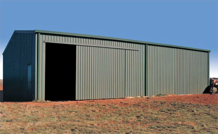 A Large Metal Building With a Sliding Door is in the Middle of a Field — Just Sheds In Kunda Park, QLD