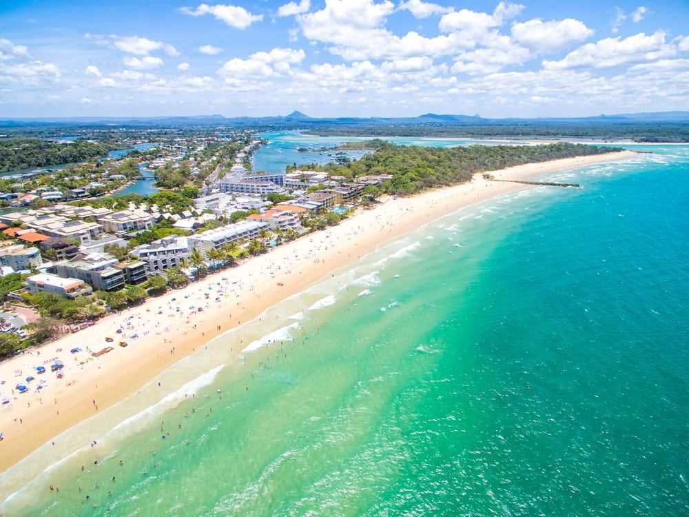 An Aerial View Of A Beach With A City In The Background — Just Sheds In Sunshine Coast, QLD