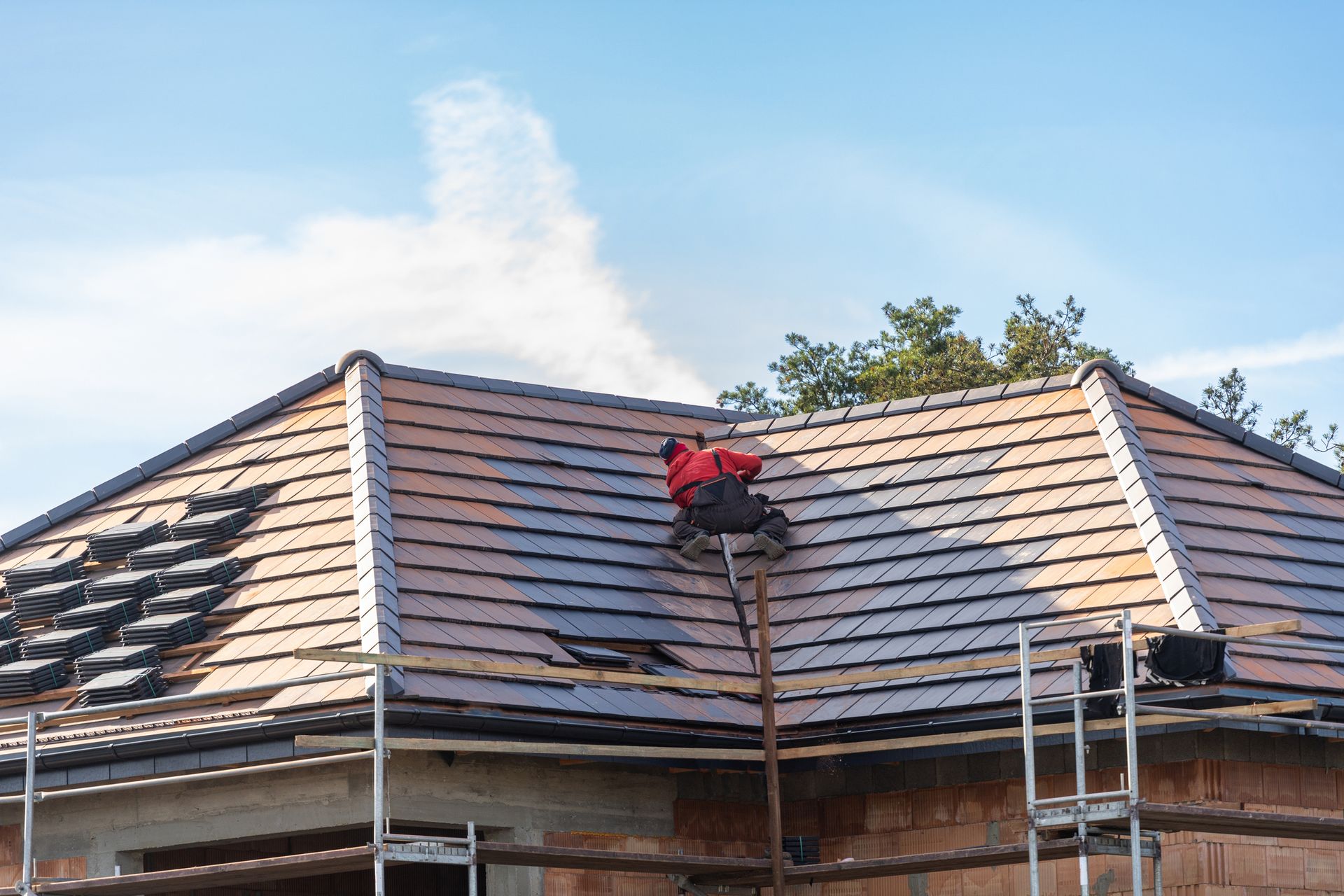 A man performing roofing replacement work on a rooftop, showcasing skilled craftsmanship. 