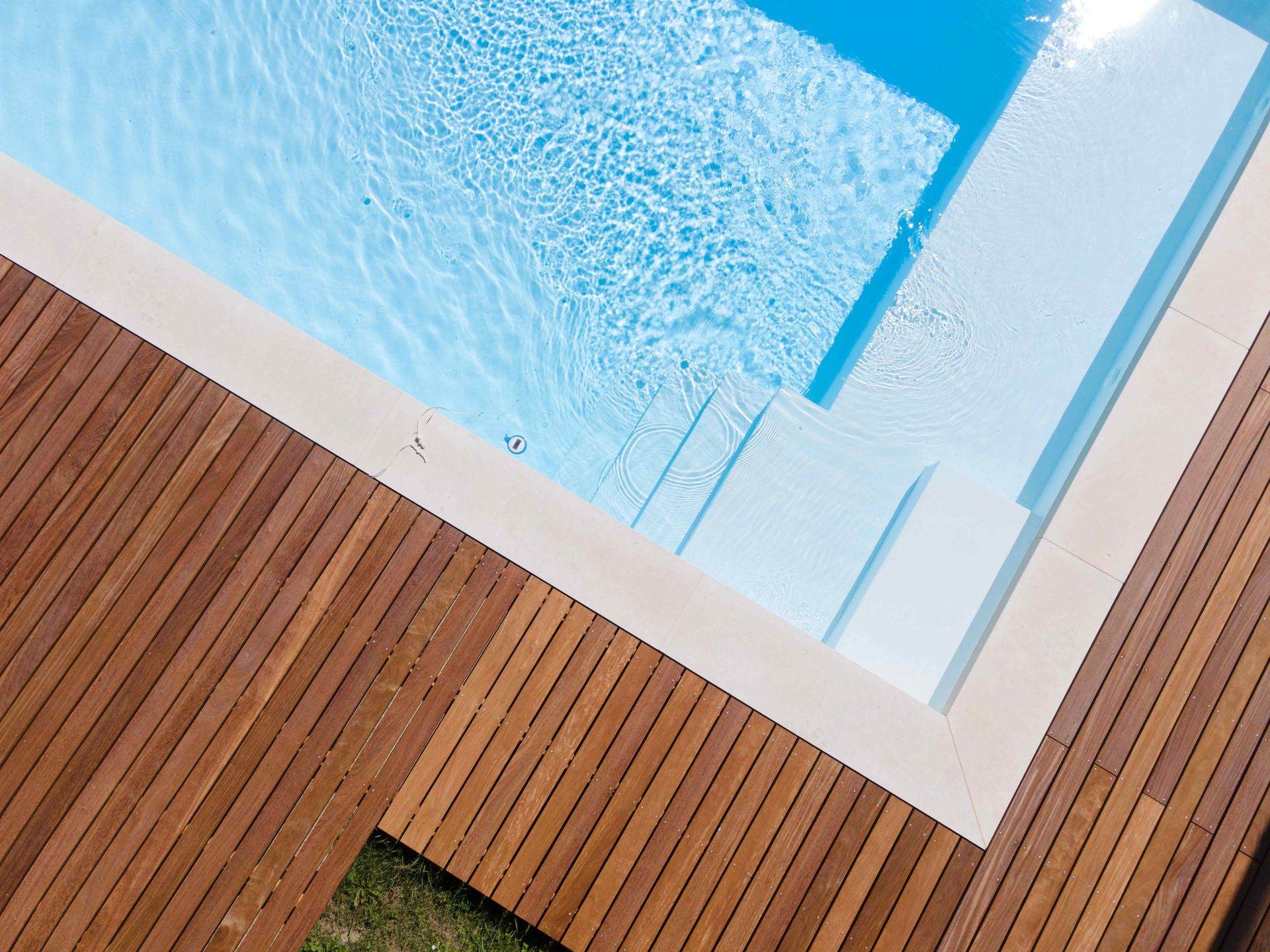 a rectangle pool surrounded by a wood deck with clear blue water