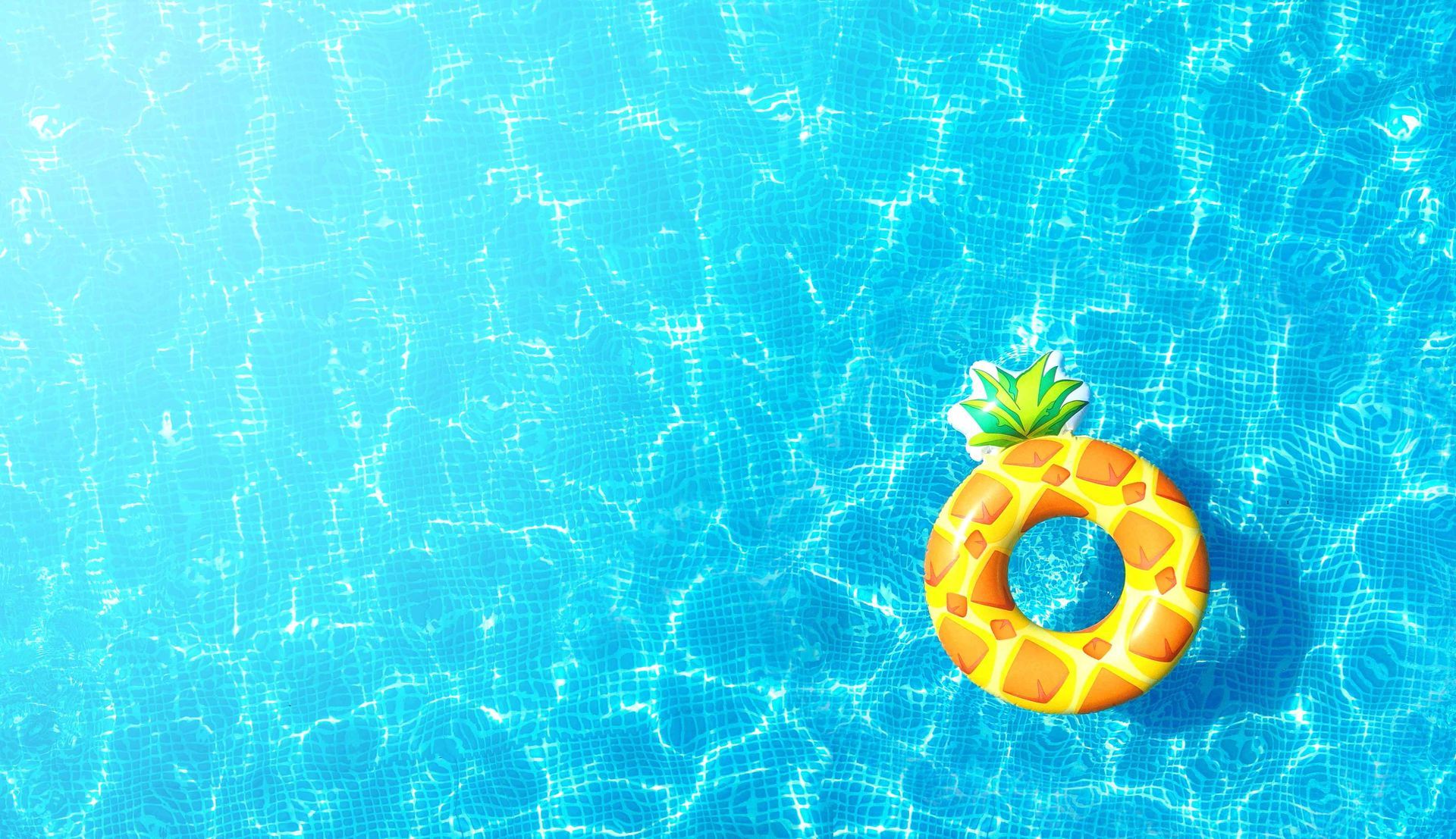 Backyard swimming pool reflecting light with a pineapple floaty in the water