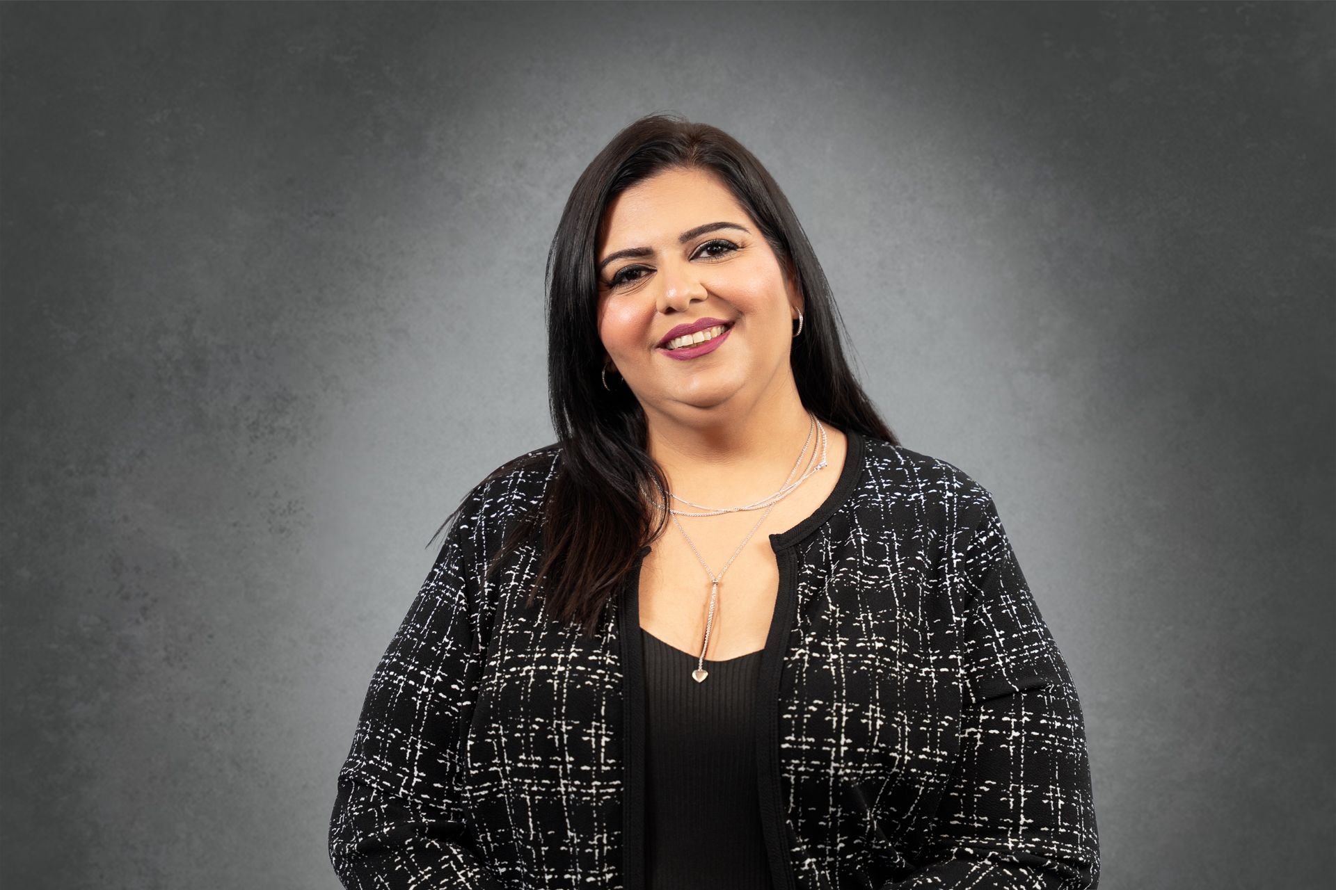 A woman in a black jacket is smiling for the camera.