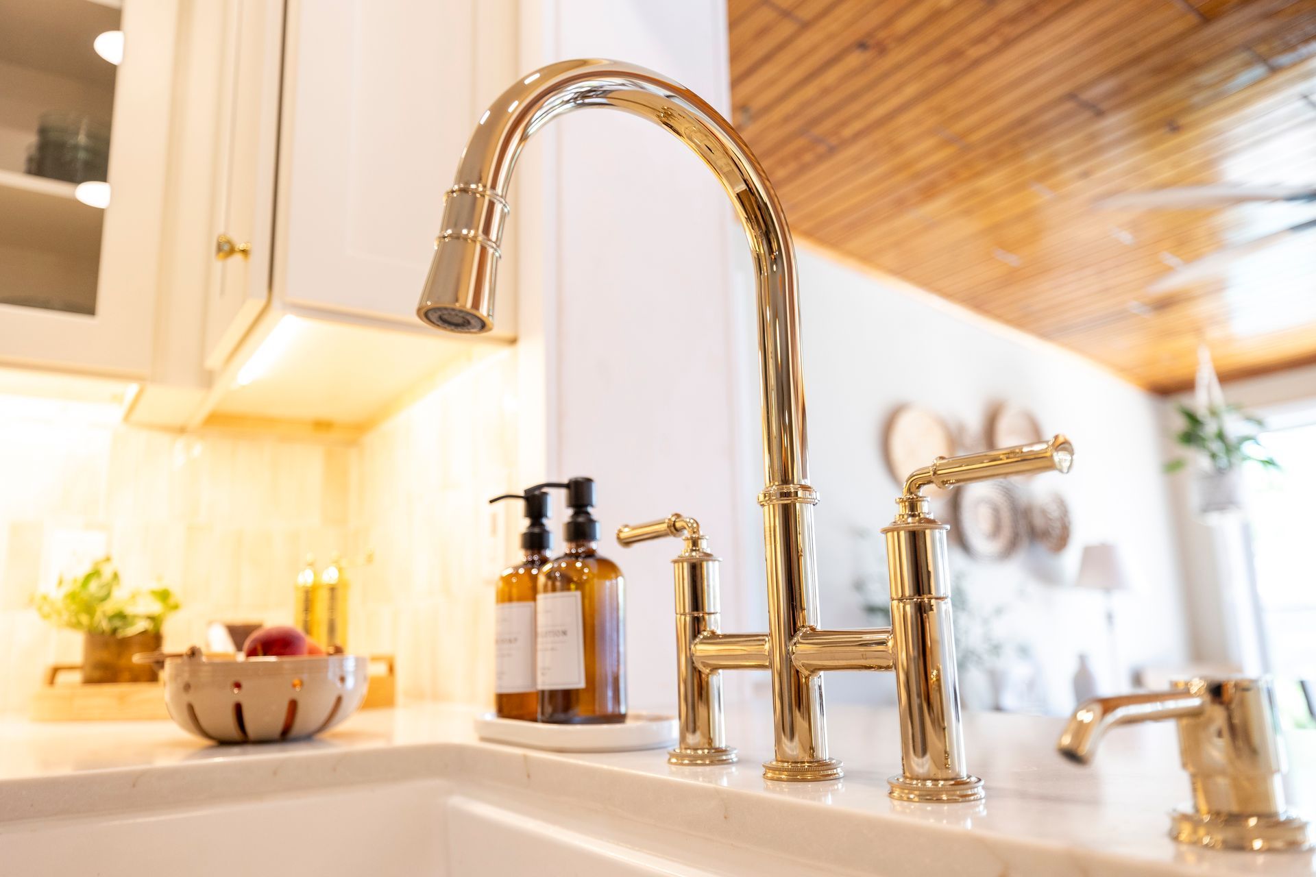 A kitchen sink with a gold faucet and soap dispensers on the counter.