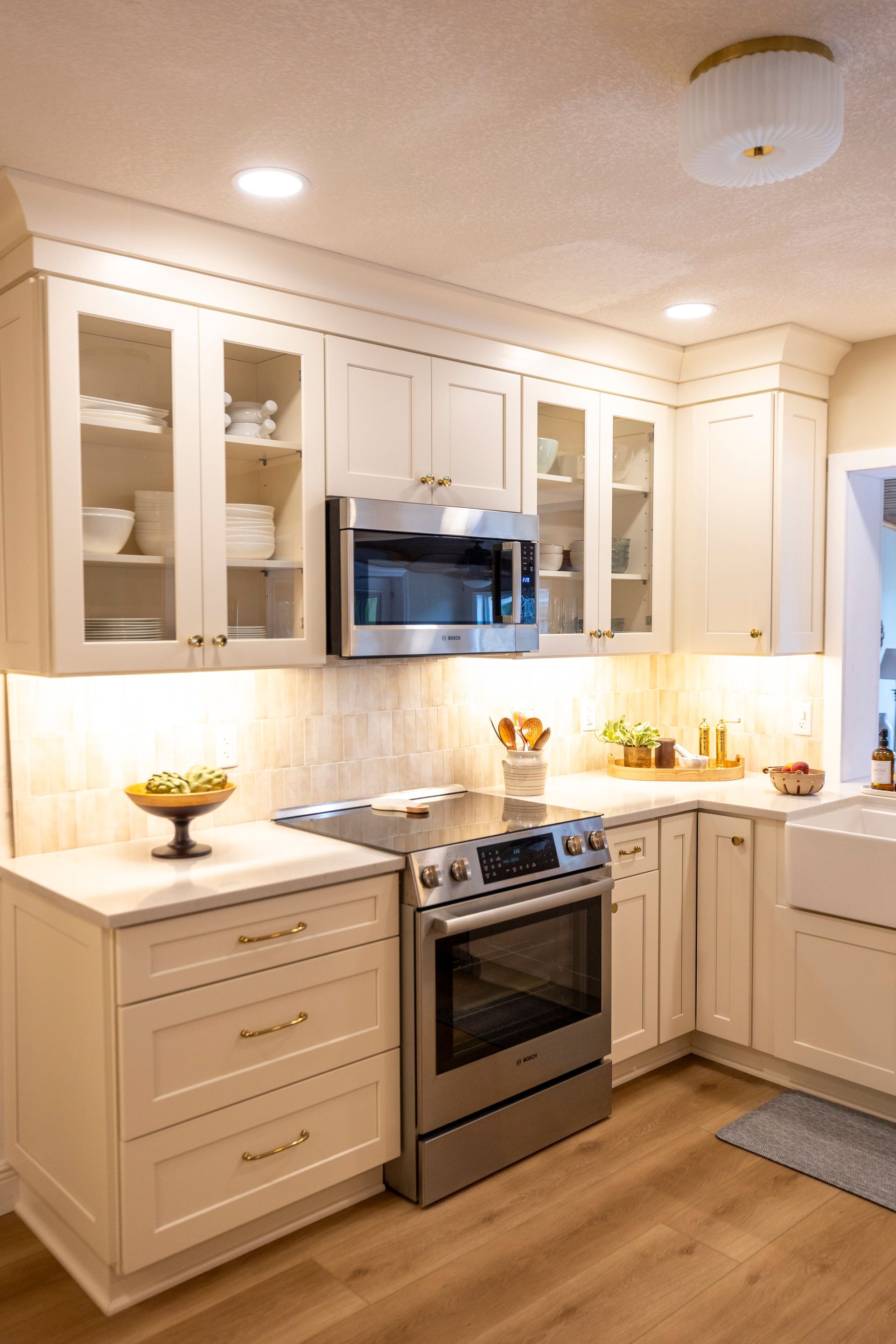 A kitchen with white cabinets , stainless steel appliances , a microwave , and a sink.