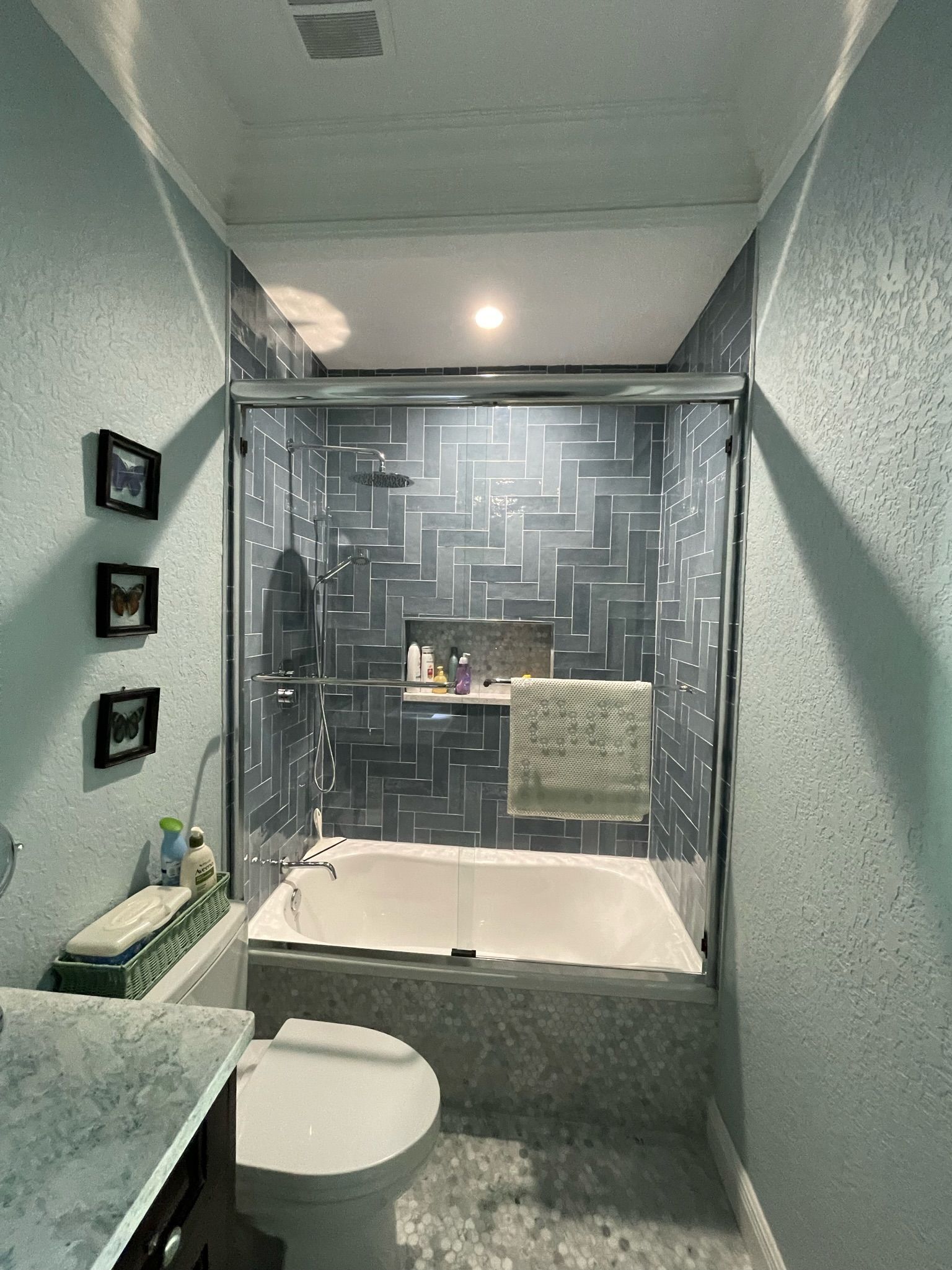 Luxe bathroom remodel: Blue herringbone tiles, deep soaking tub, sleek vanity for spa-like savings.