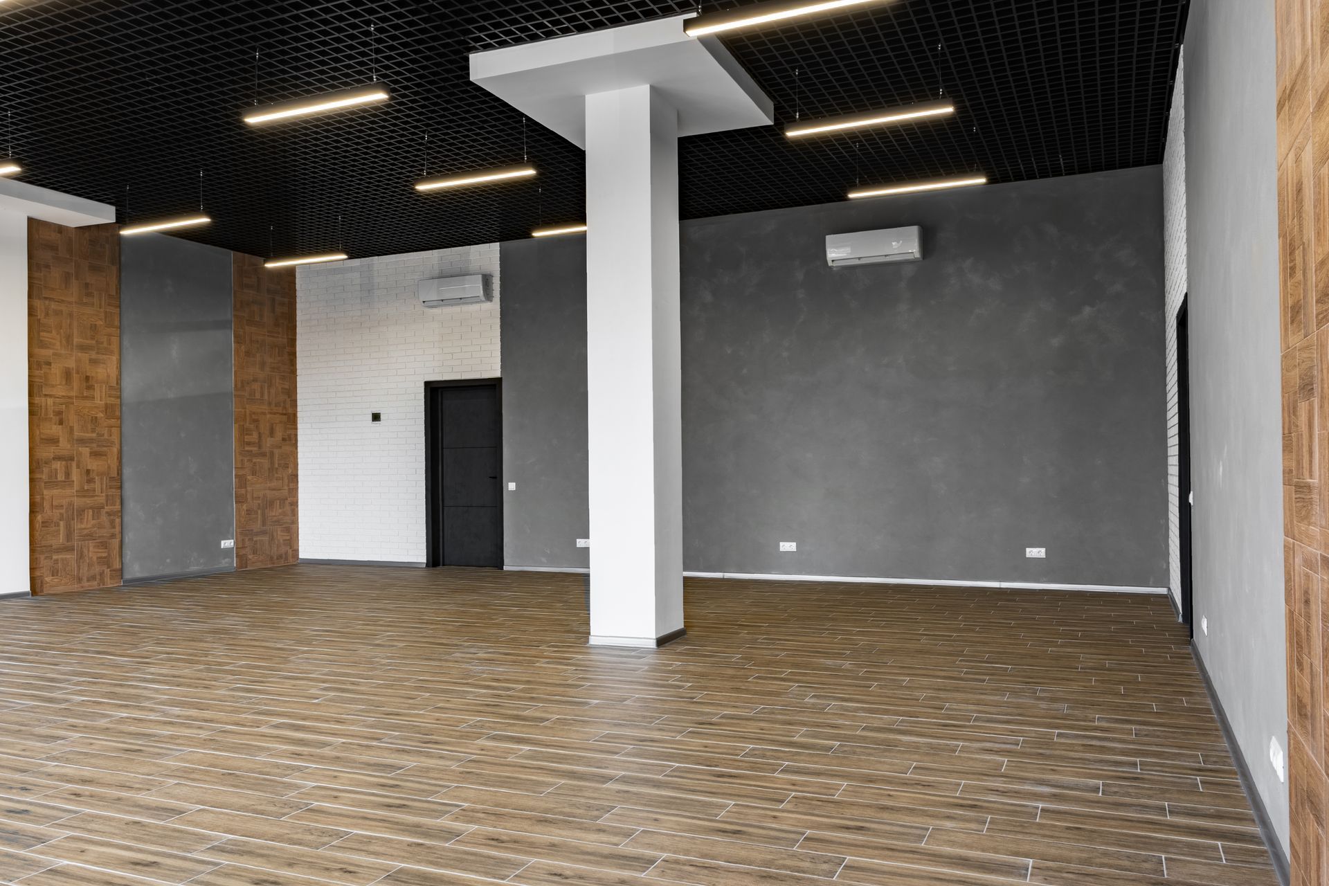 A large empty room with a wooden floor and a black ceiling.