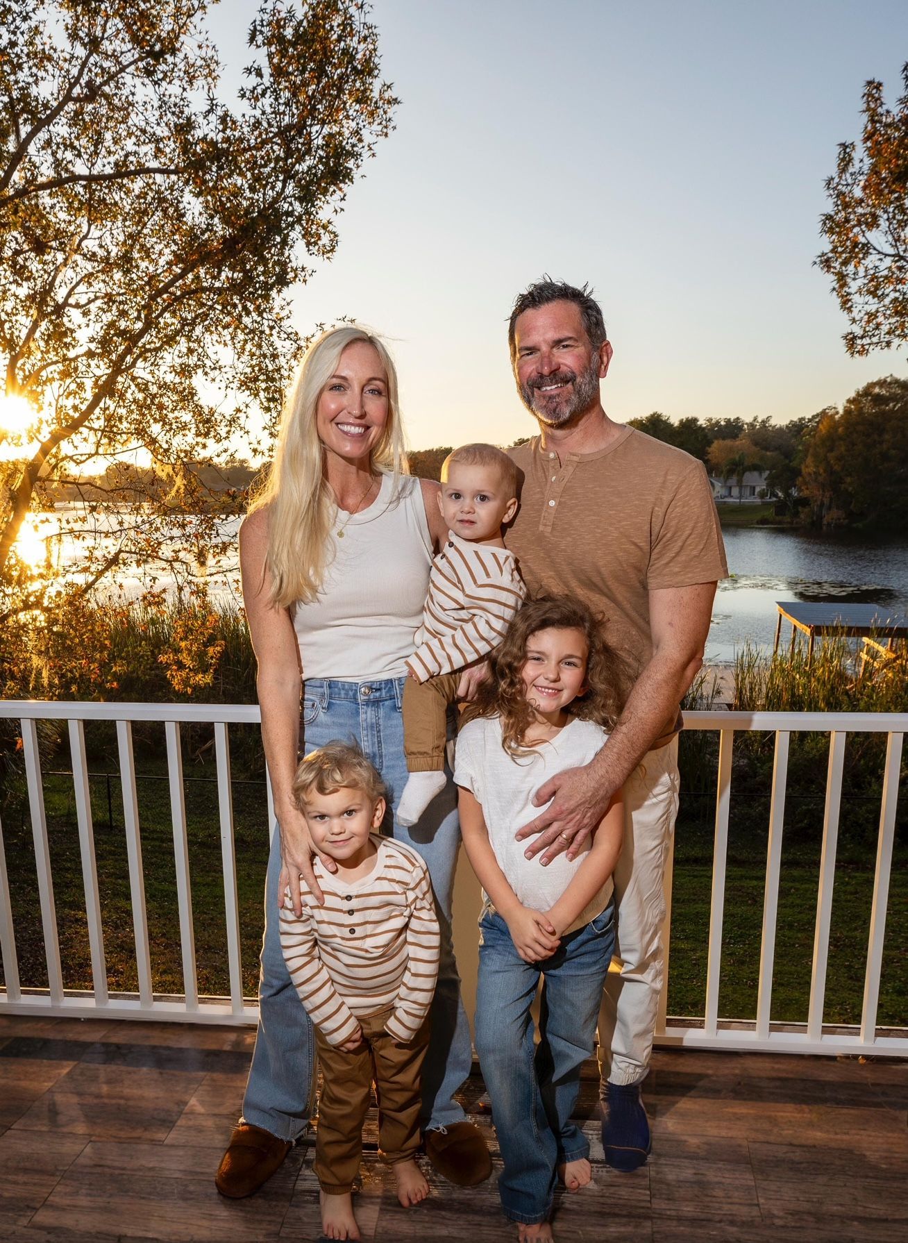 A family is posing for a picture on a deck with a lake in the background.