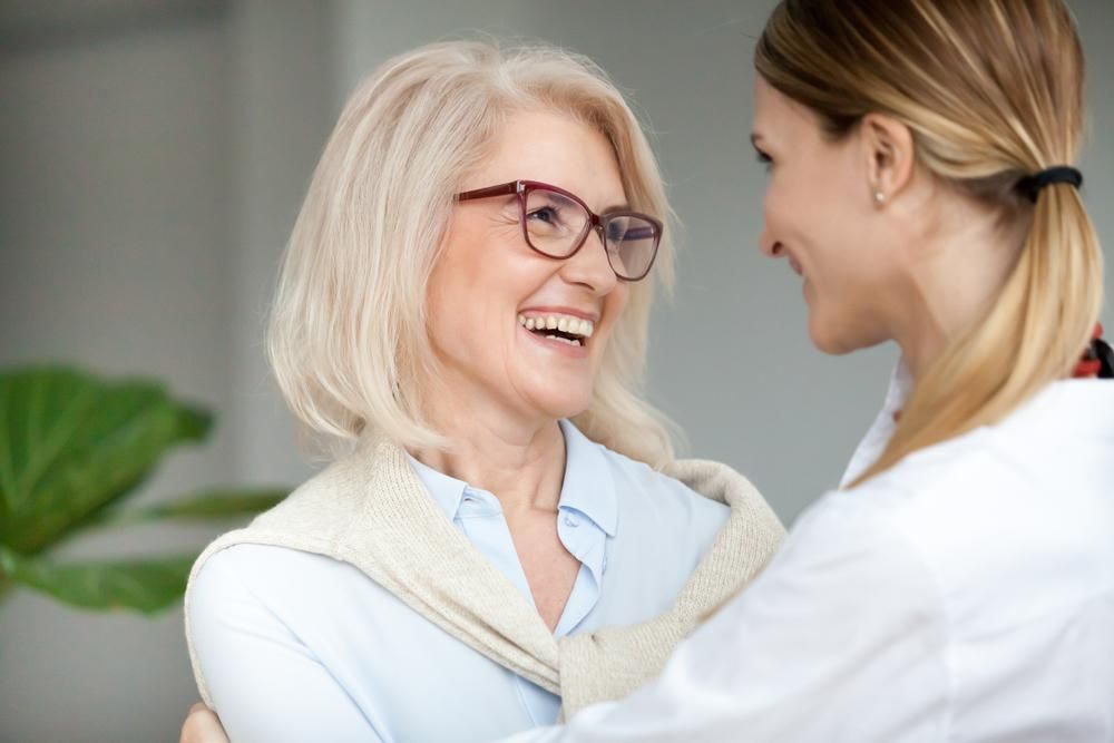 A Nurse Is Hugging An Older Woman Who Is Wearing Glasses — Howells & Co Legal & Conveyancing In Wollongong, NSW
