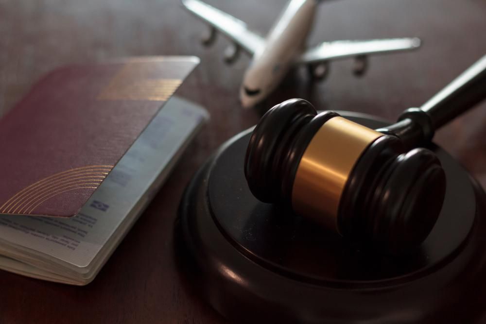 A Judge 's Gavel Is Sitting On A Wooden Table Next To A Passport And An Airplane — Howells & Co Legal & Conveyancing In Cessnock, NSW
