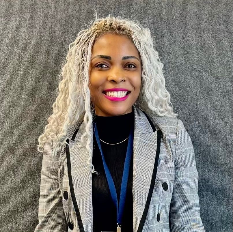 A Woman In A Blue Shirt Is Sitting In A Pink Chair — Howells & Co Legal & Conveyancing In Cessnock, NSW