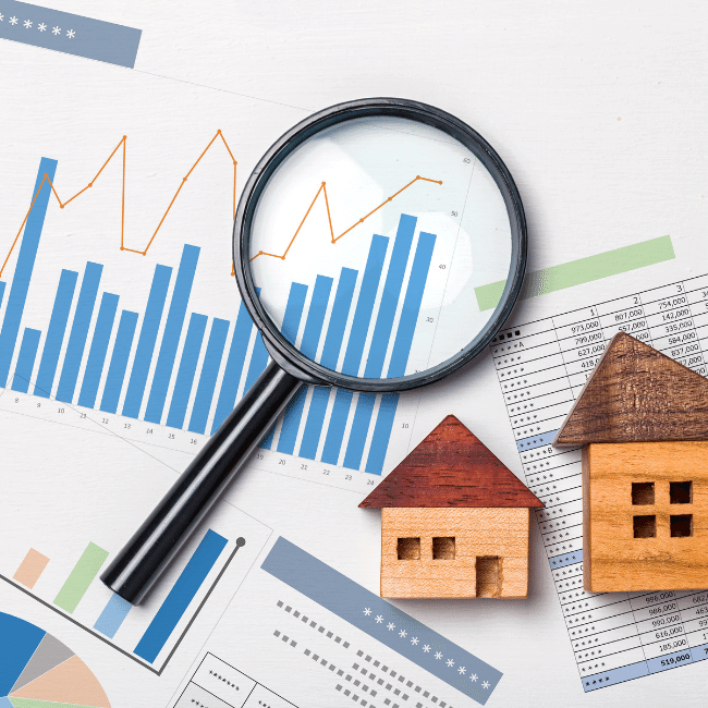 A Magnifying Glass Is Sitting On Top Of A Table Next To Two Small Houses — Howells & Co Legal & Conveyancing In Cessnock, NSW