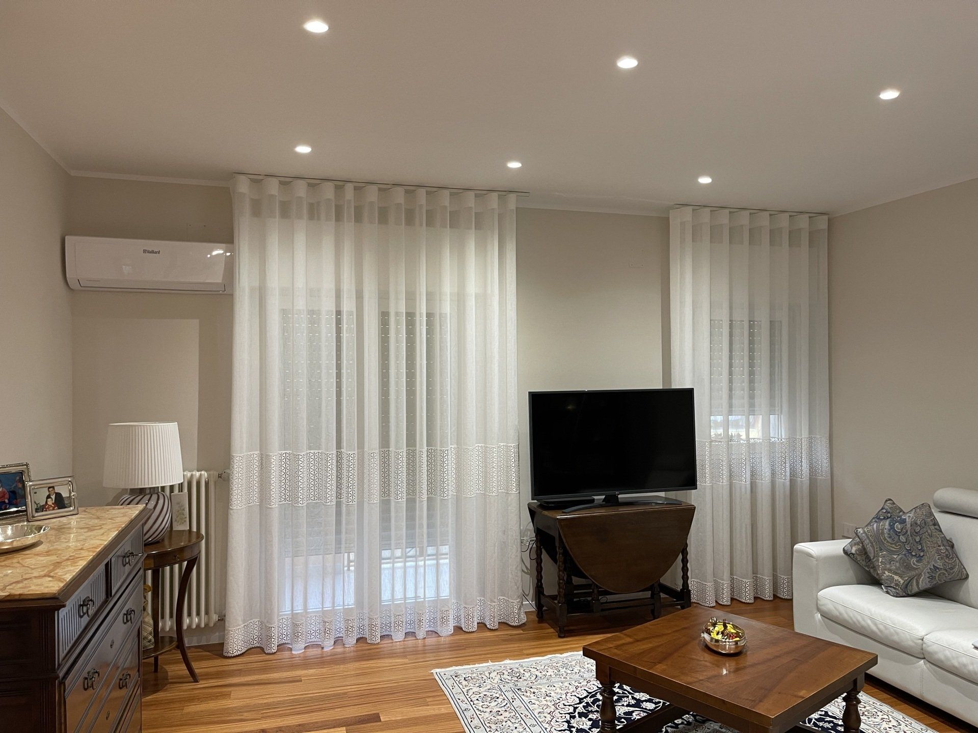 Un soggiorno con divano, tavolo, televisione e tende.