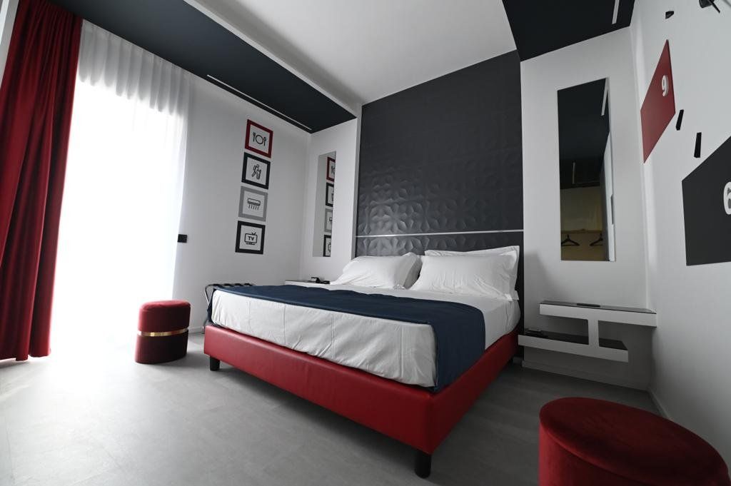 Una camera d'albergo con un letto grande e pouf rossi