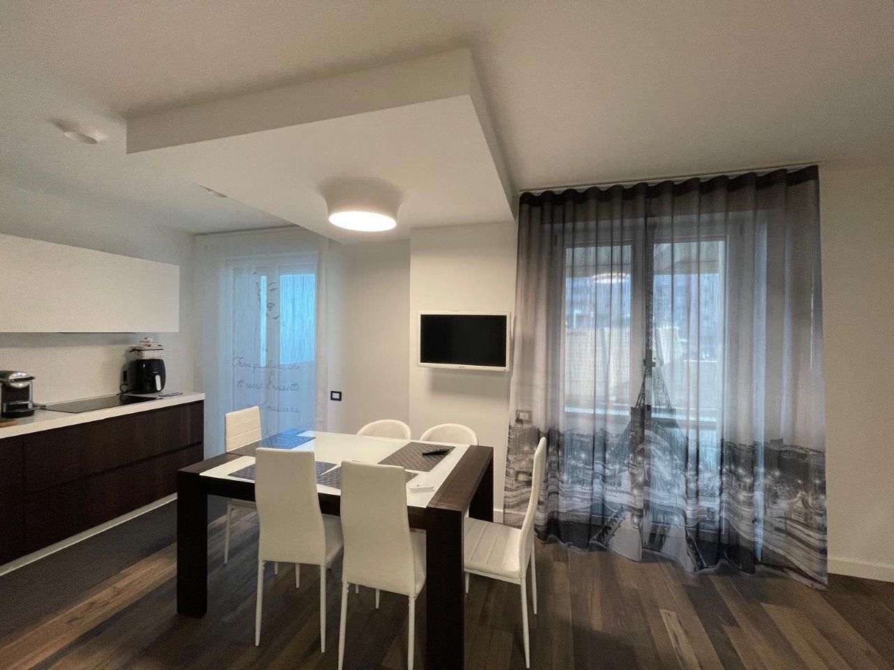 Una sala da pranzo con tavolo, sedie e una televisione a parete.