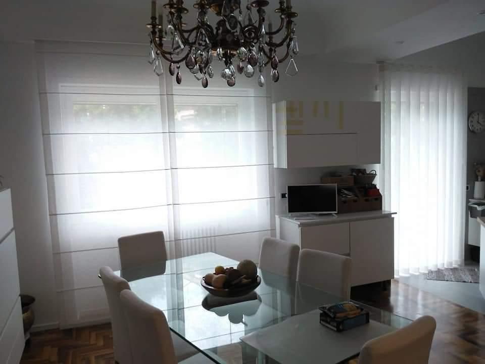 Una sala da pranzo con tavolo e sedie in vetro e un lampadario.