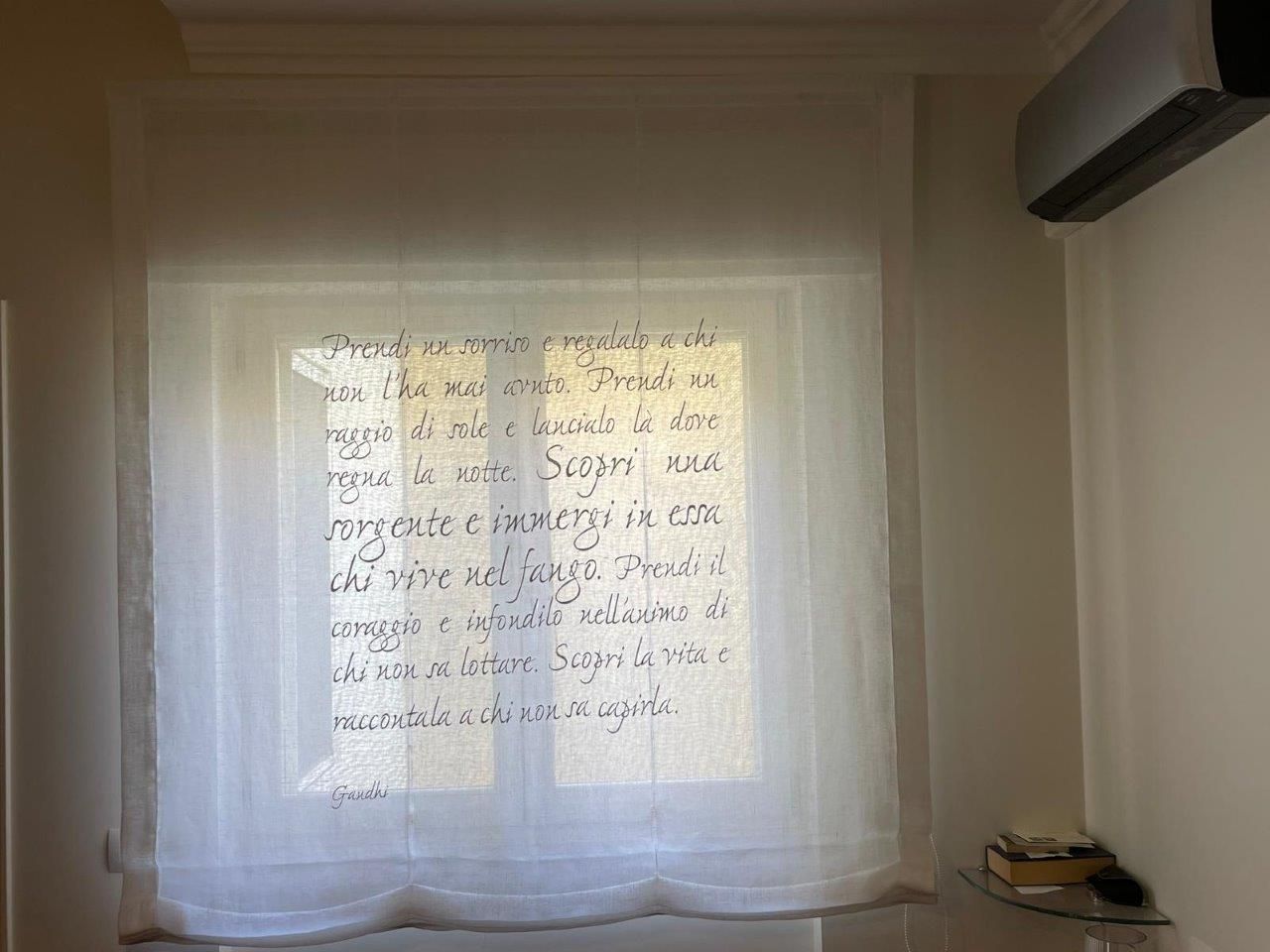 Una tenda bianca con una scritta è appesa a una finestra.