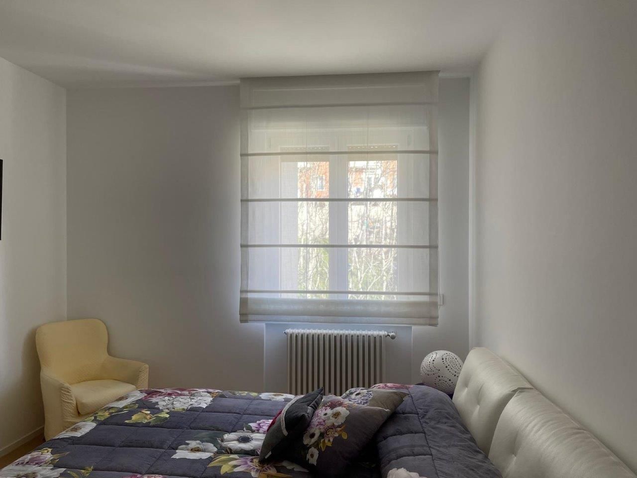 Una camera da letto con un letto, una sedia e una finestra