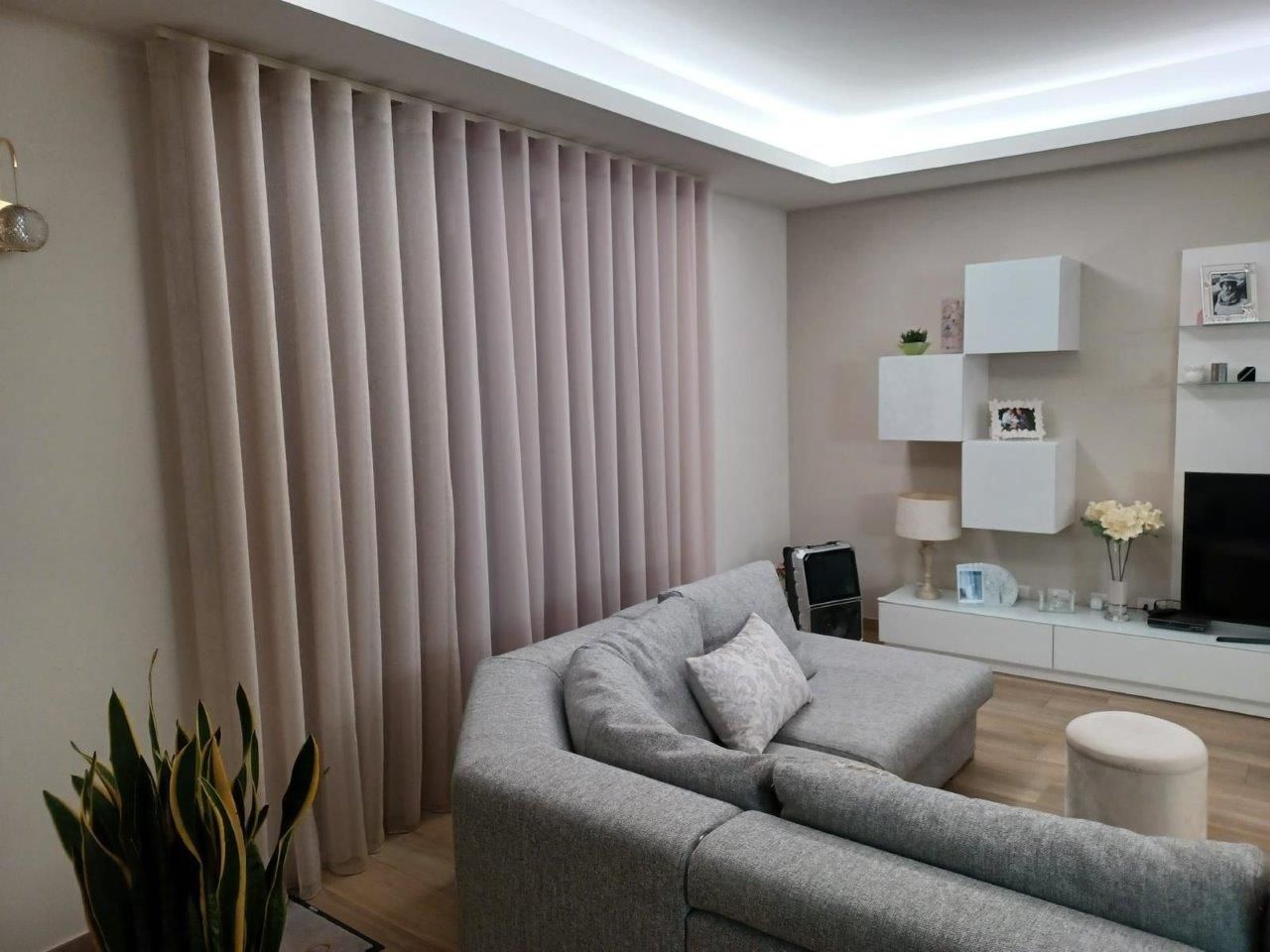 Un soggiorno con divano, televisione e tende.