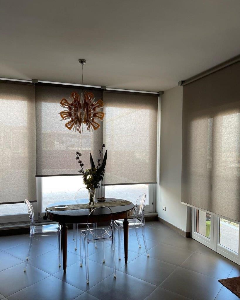 Una sala da pranzo con tavolo, sedie e un lampadario appeso al soffitto.