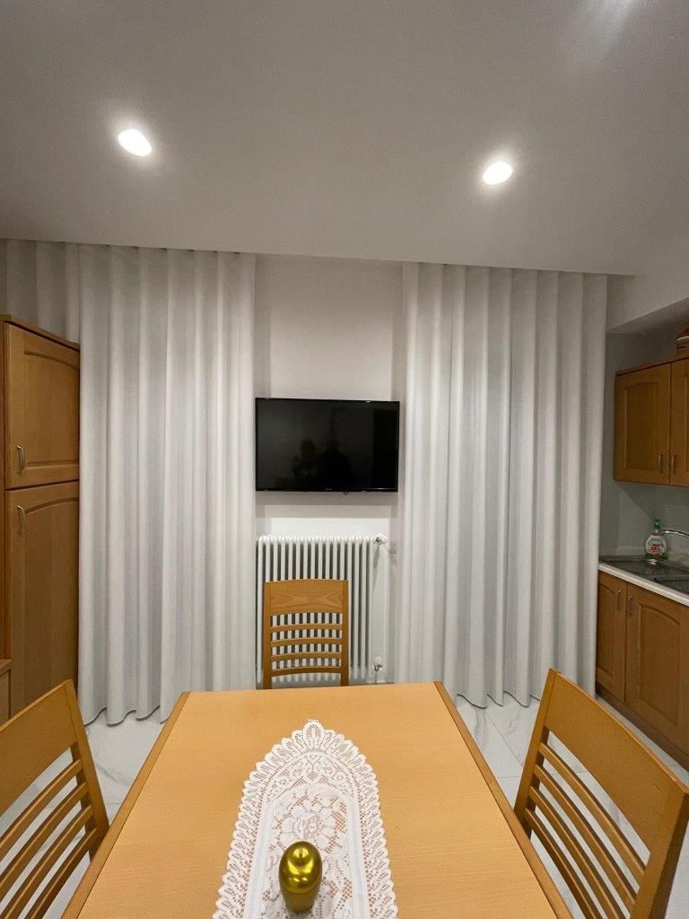 Una sala da pranzo con tavolo, sedie e TV a schermo piatto sulla parete.