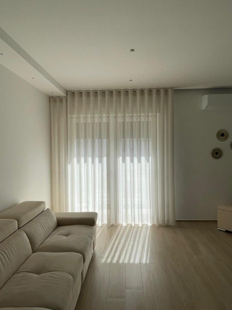 Un soggiorno con un divano, tende e una finestra.