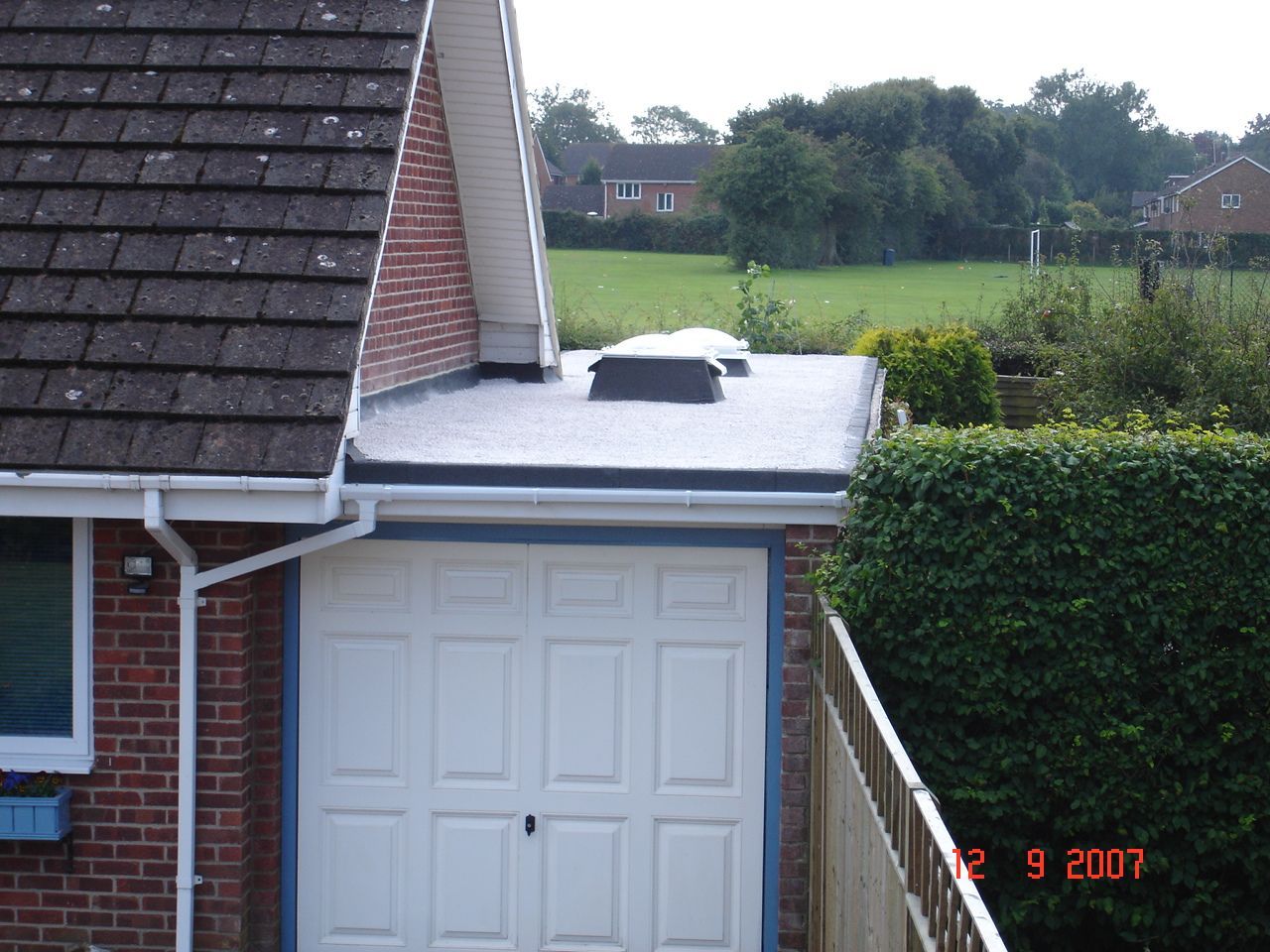 A garage with a white door and a flat black roof.