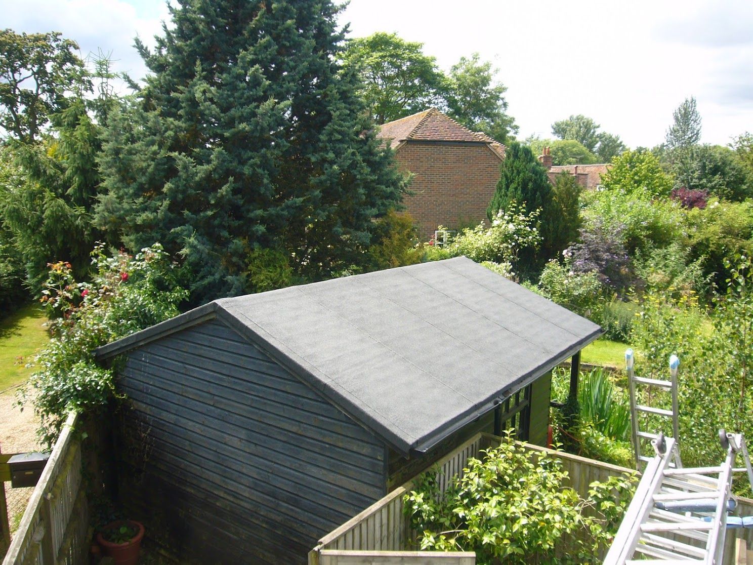 A view from a building roof, showing a newly painted, flat gray surface with buckets, and a brown border.