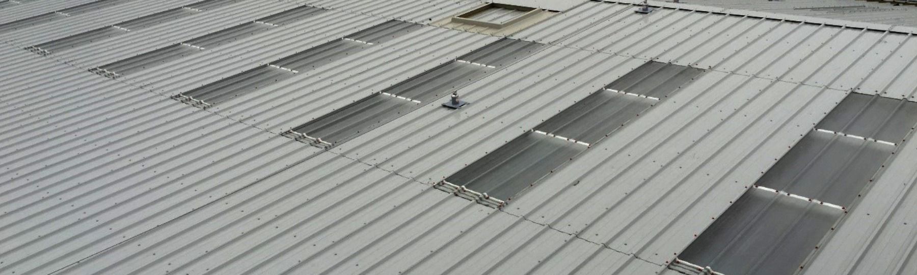 An aerial view of a metal roof with several rectangular skylights.
