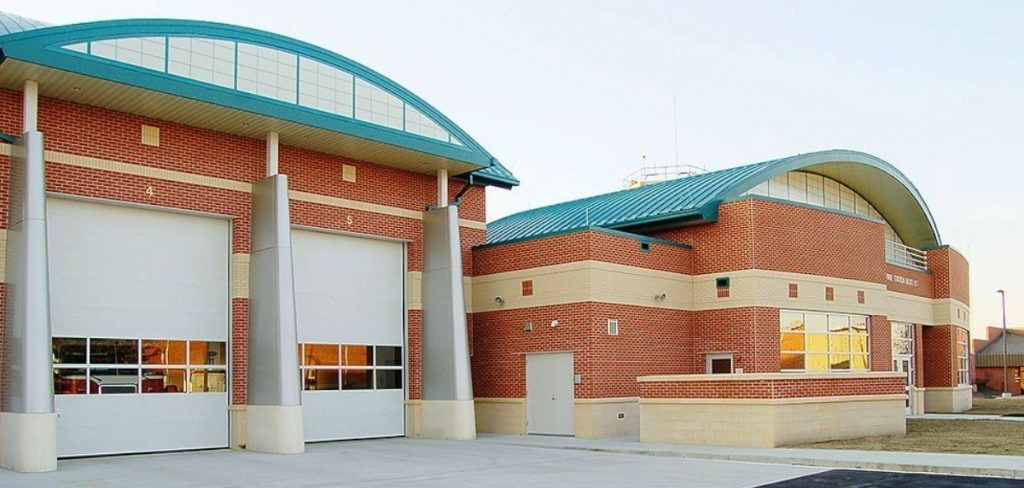 Aerial view of a multi-sectioned building with a grey metal roof.