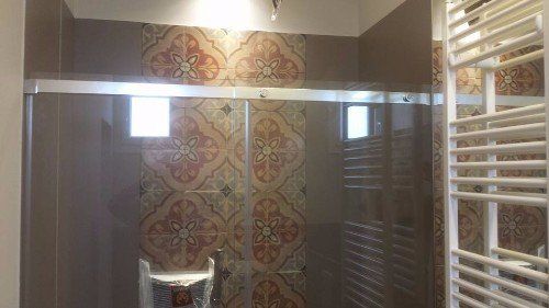 cabina doccia con parete decorata con maiolica