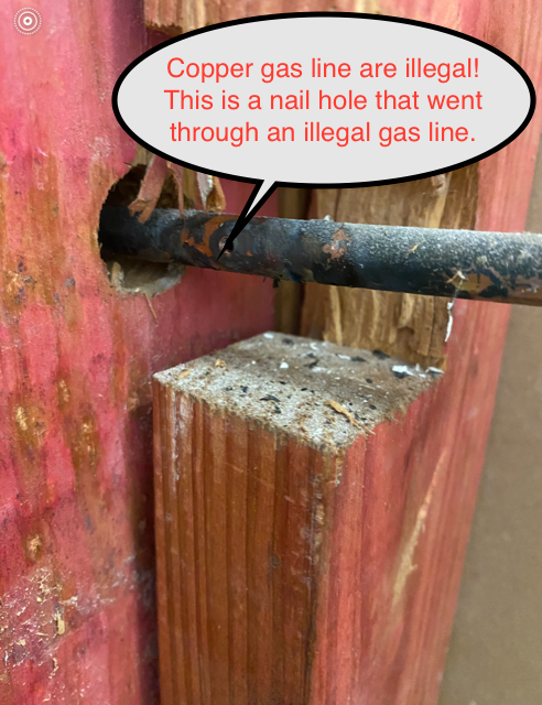 Close-up of a copper gas line with a nail hole. Text indicates copper is illegal and the hole punctured the line.