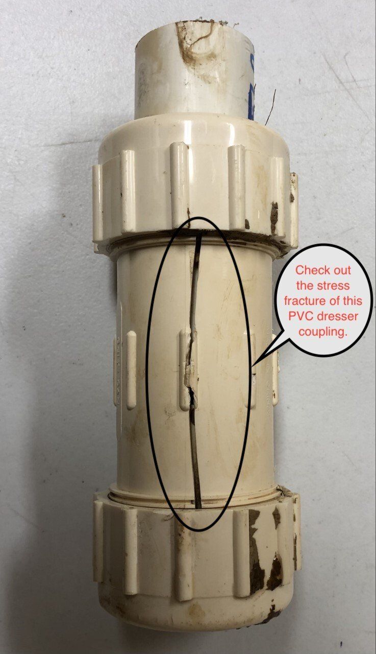 A cracked, beige PVC inline check valve coupling.