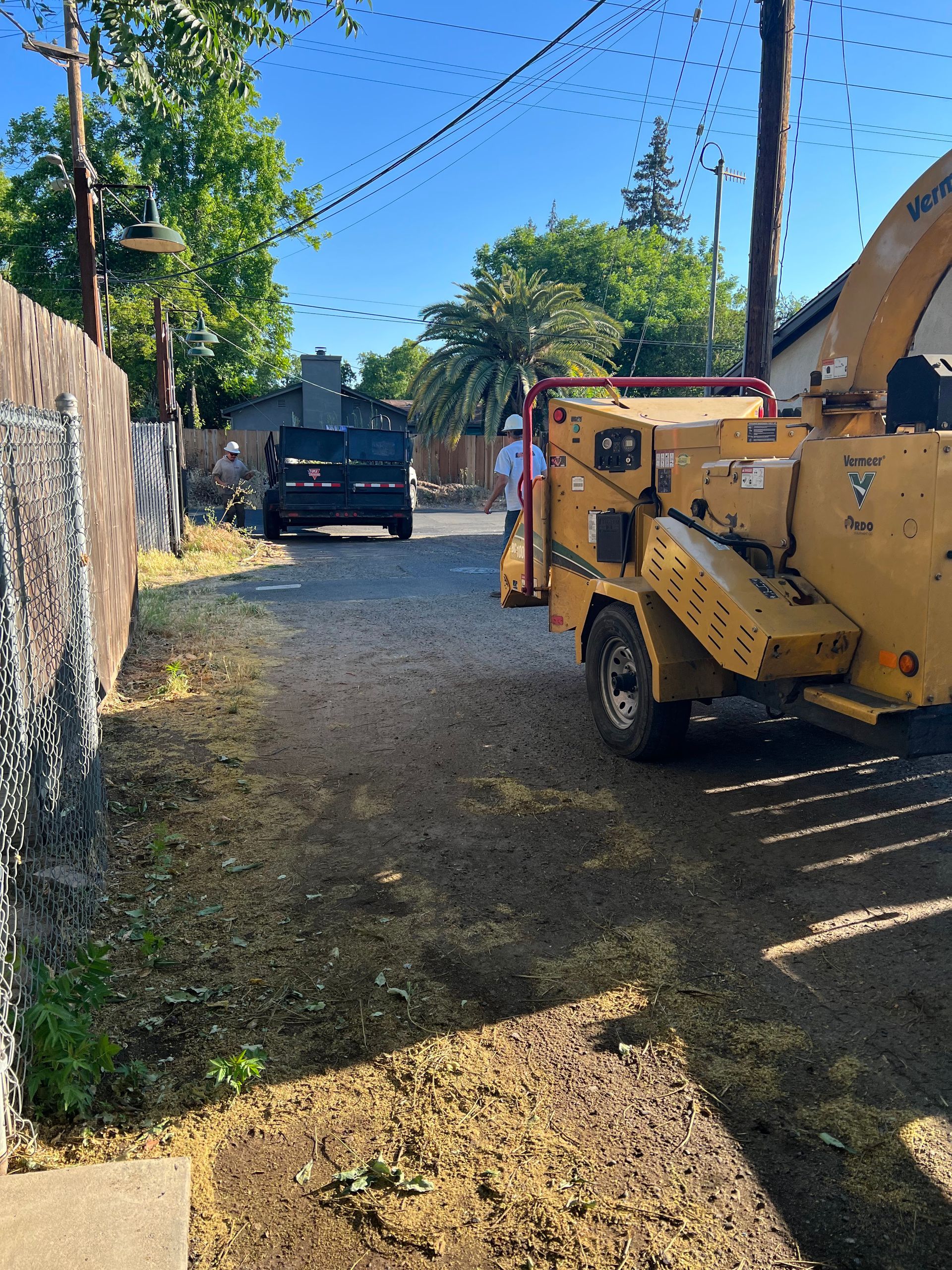 A yellow truck is parked on the side of the road next to a fence.