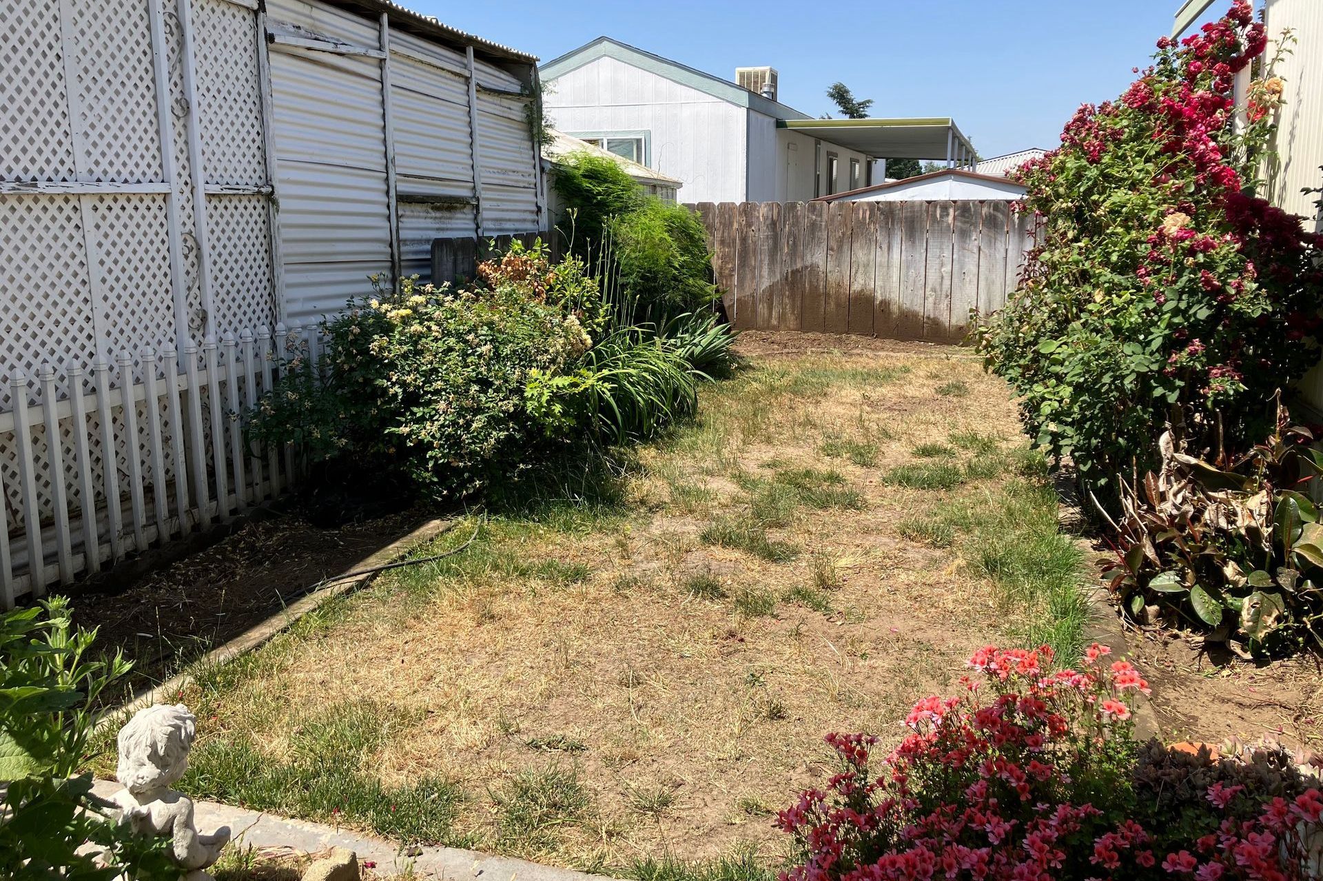 A backyard with a white picket fence and flowers.