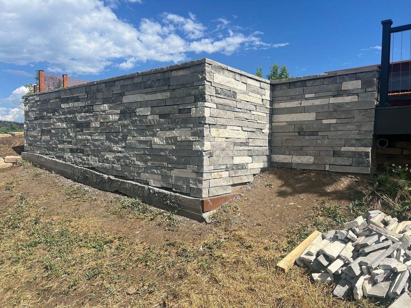 Stone retaining walls on a grassy construction site under a blue sky.