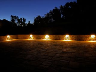 Night view of a southwestern-style home with pathway lighting, a lounge chair, and a decorative arched door.