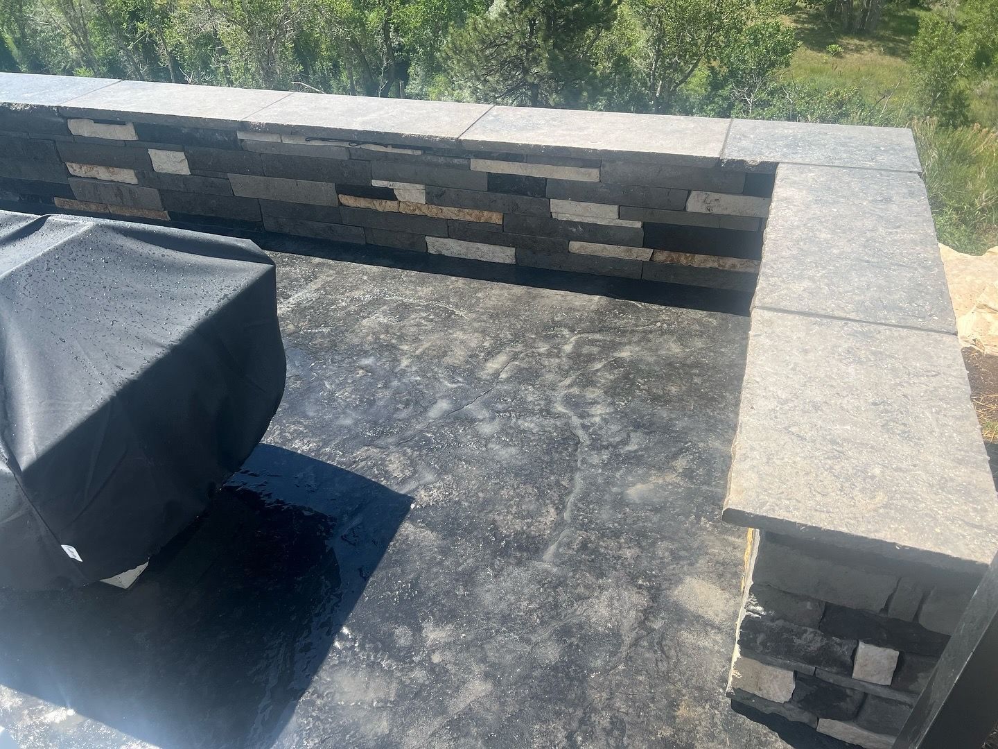 Stone patio with stacked stone wall and furniture cover.