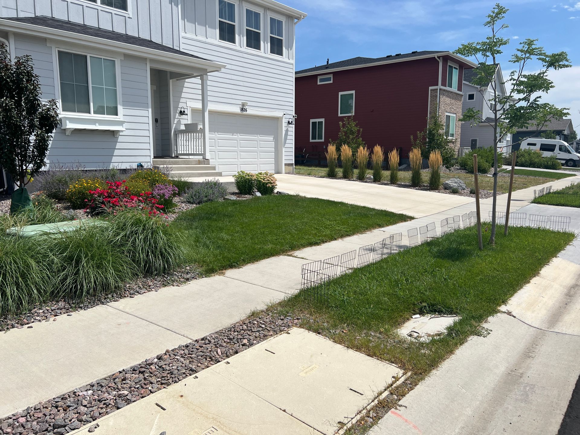 Suburban homes with landscaped yards. Lawn and driveway in foreground. Blue sky.