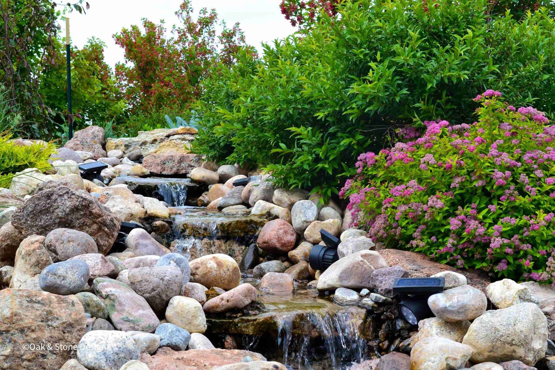 Stone steps and retaining walls in landscaped garden, lined with green shrubs and flowers.