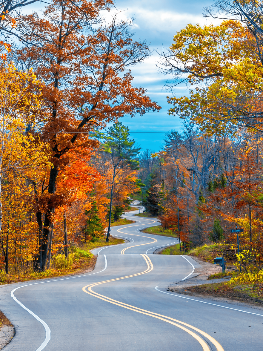 A wooden walkway leading to a gazebo overlooking a body of water at sunset.
