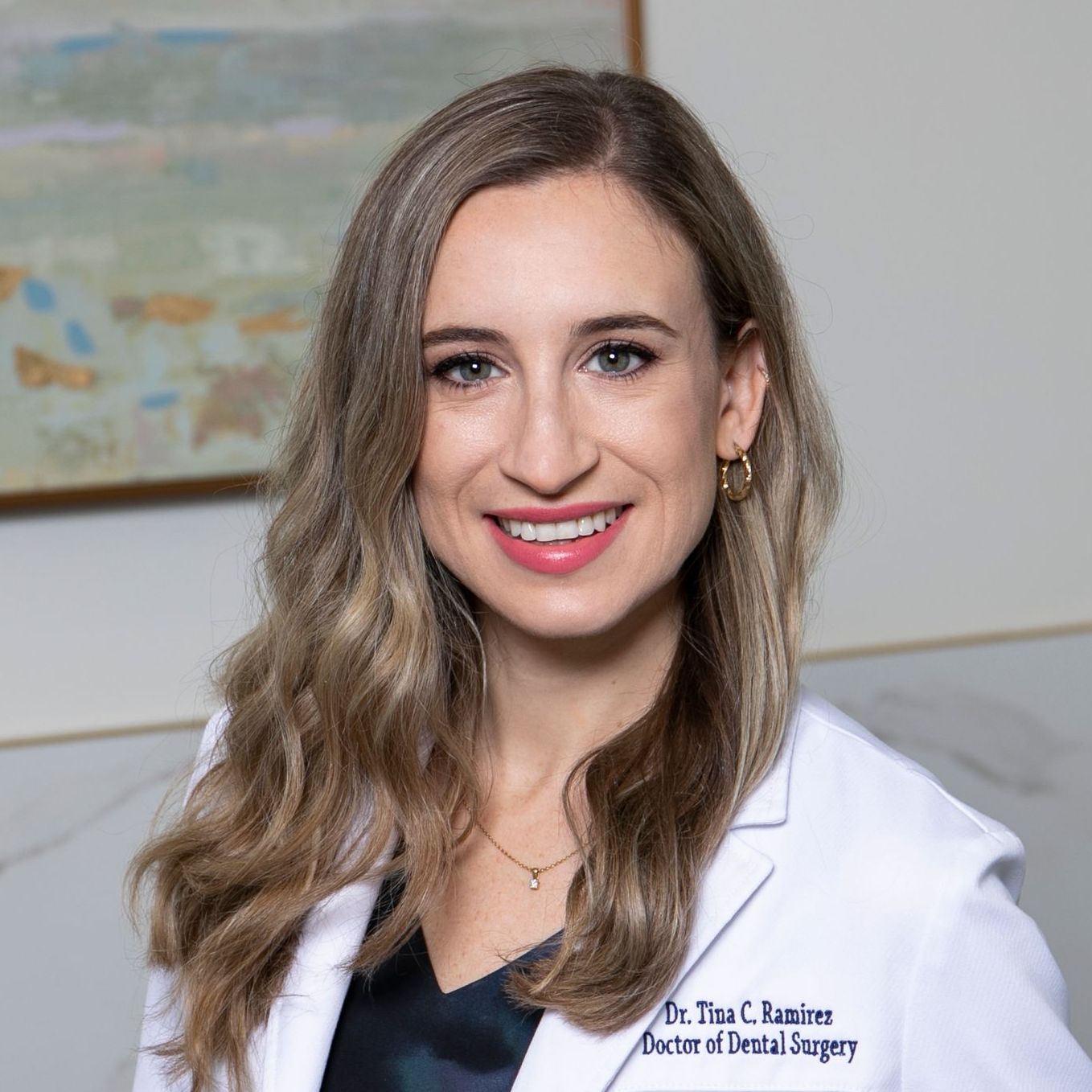 A woman in a white lab coat is smiling for the camera.